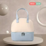 Bolso nevera beige y azul claro para leche materna, con dos compartimentos y asas, sobre plataforma circular.