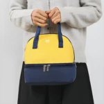 Bolso nevera amarillo y azul para leche materna con dos compartimentos y asas cortas.