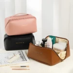 Bolso organizador de maquillaje rosa, negro y marrón. Uno abierto con productos de belleza.