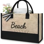 Bolso de playa yute beige y negro con "Beach" y ramo de flores.