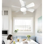 Ventilador de techo blanco con luz LED, 5 aspas, instalado en cocina con niña tomando jugo.