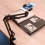 Brazo soporte negro para celular sobre álbum de fotos, ideal para digitalizar recuerdos.