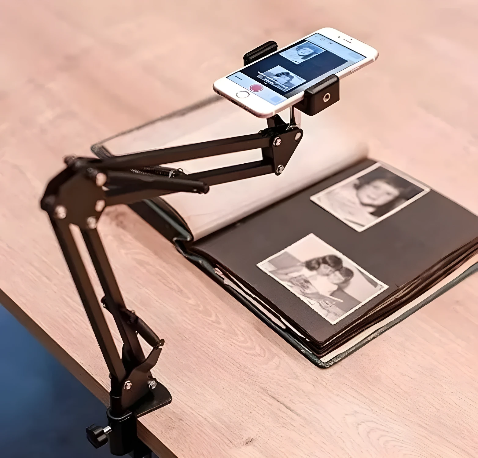 Brazo soporte negro para celular sobre álbum de fotos, ideal para digitalizar recuerdos.
