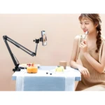 Brazo flexible negro para celular, tablet o cámara, ideal para video llamadas, transmitiendo a una mujer comiendo un postre.
