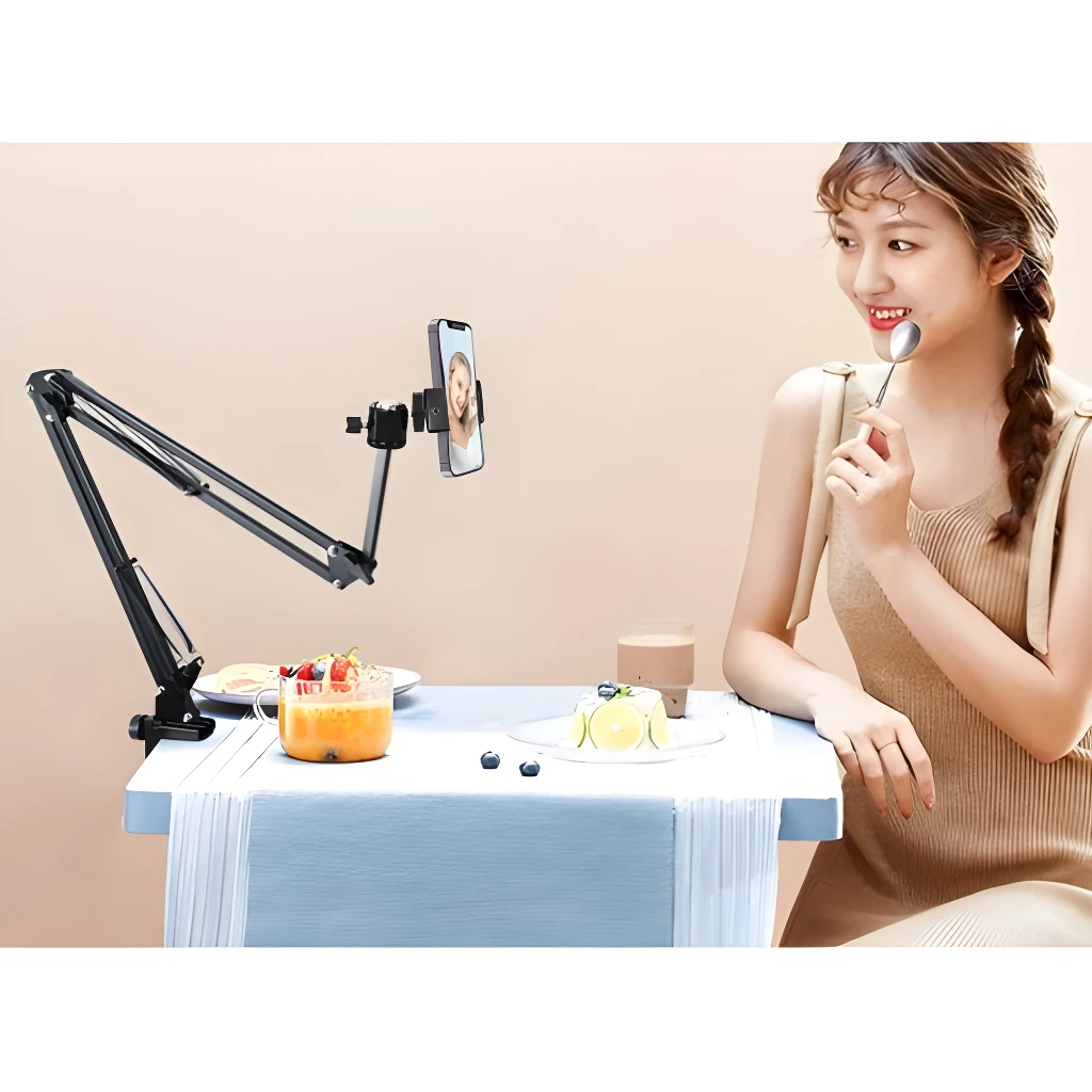 Brazo flexible negro para celular, tablet o cámara, ideal para video llamadas, transmitiendo a una mujer comiendo un postre.