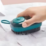 Cepillo dispensador de jabón verde y negro limpiando tela blanca con espuma.