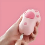 Cepillo para mascota con vapor rosa con forma de huella de pata, conectado a cable de carga.