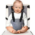 Bebé sonriente con arnés de seguridad gris para silla alta.