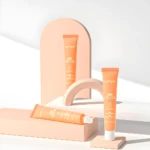 Crema depilatoria facial JoyPretty 60s en envase naranja, sobre fondo minimalista de bloques de colores pastel.