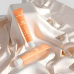 Crema depilatoria JoyPretty 60s color naranja, dos tubos sobre tela satinada color crema.