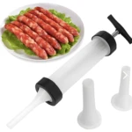 Embutidor manual de salchichas y chorizos blanco, con tres embudos, y salchichas crudas en lechuga.