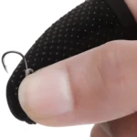 Guante protector negro para pescar con superficie texturizada y anzuelo incrustado en el dedo.