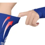 Manga de voleibol azul, mano estirando la tela elástica, detalle de flechas rojas que indican elasticidad.