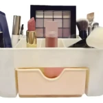 Organizador de maquillaje blanco con compartimentos, incluyendo un cajón inferior, para cosméticos y brochas.