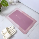 Tapete de baño antideslizante rosa 60x40cm junto a pantuflas blancas.