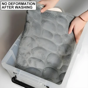 Tapete de baño gris con textura de piedras suaves, sin deformación tras lavado, dentro de caja plástica.