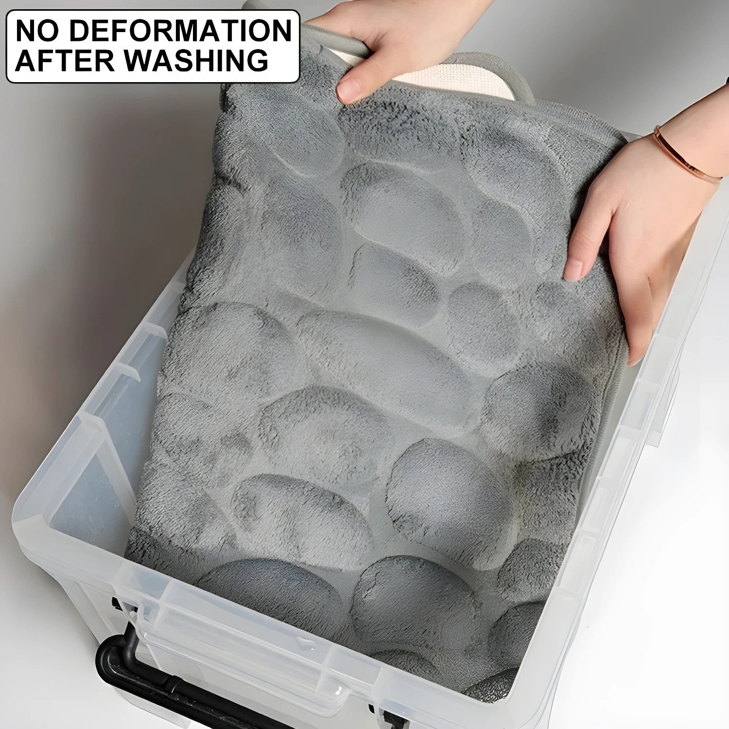 Tapete de baño gris con textura de piedras suaves, sin deformación tras lavado, dentro de caja plástica.