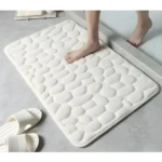 Tapete de baño blanco con textura de piedras suaves, ideal para absorber agua y antideslizante.