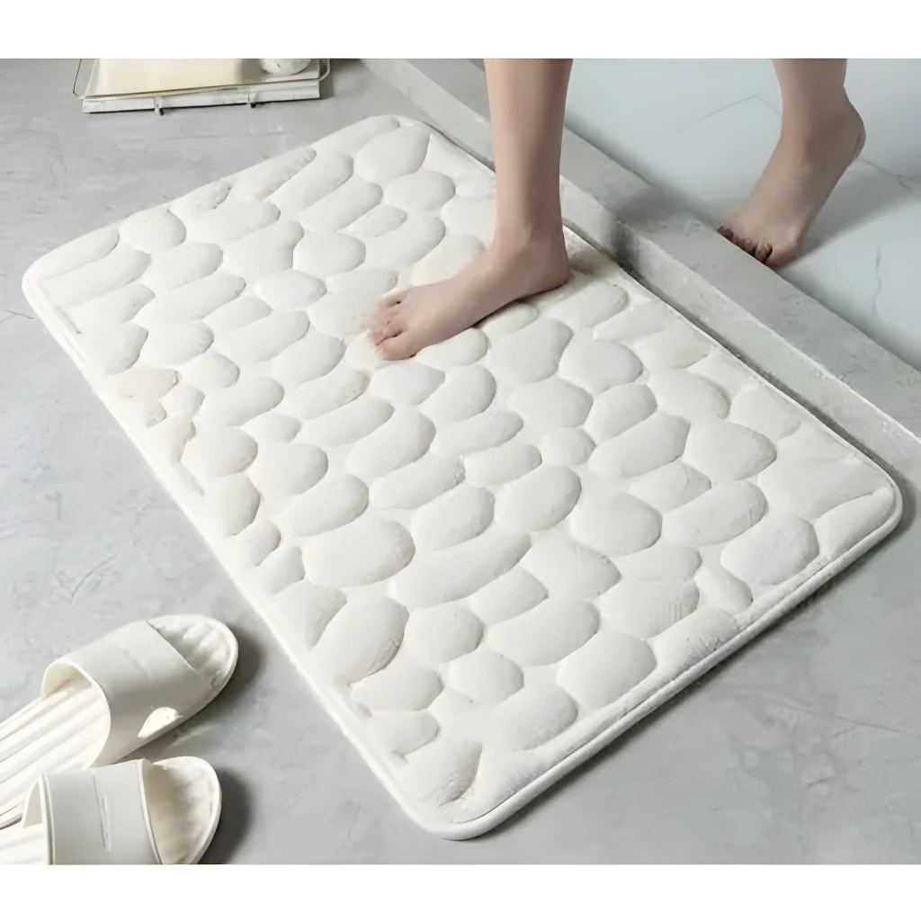Tapete de baño blanco con textura de piedras suaves, ideal para absorber agua y antideslizante.