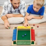 Padre e hijo juegan "Cierra la Caja" de madera, con dados y fichas de colores.