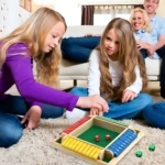 Juego "Cierra La Caja" de madera con dados rojos y verdes, jugado por dos niñas en alfombra mullida.
