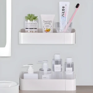 Estante adhesivo blanco con productos de baño: jabón líquido, loción, crema dental, cepillo y planta.