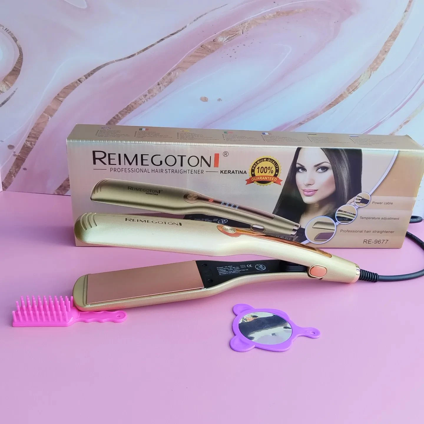 Plancha de cabello profesional Reimegoton dorada, con caja, peine pequeño rosa y espejo de mano morado sobre superficie rosa, diseño para alisar y ondular.