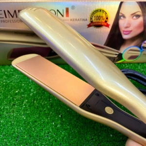 Plancha de cabello Reimegoton dorada con placas de cerámica color cobre, abierta sobre su caja de empaque que muestra a una modelo profesional.