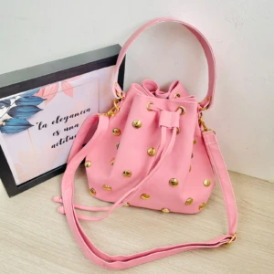 Bolso carriel tipo balde rosa vibrante en cuero sintético con taches dorados y cordón ajustable.