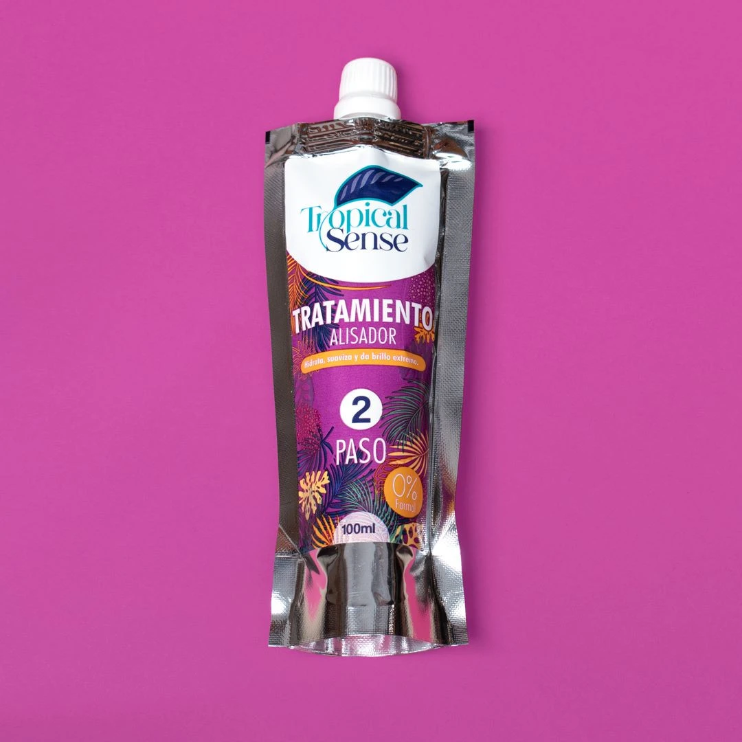 Envase de 100ml de Tratamiento Alisador paso 2 de Tropical Sense, empaque plateado con diseño tropical y violeta, fondo liso color magenta intenso.
