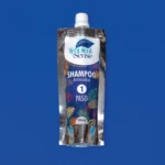 Envase flexible plateado de 100 ml con champú antiresiduos Tropical Sense, paso 1 del tratamiento, sobre fondo azul sólido.