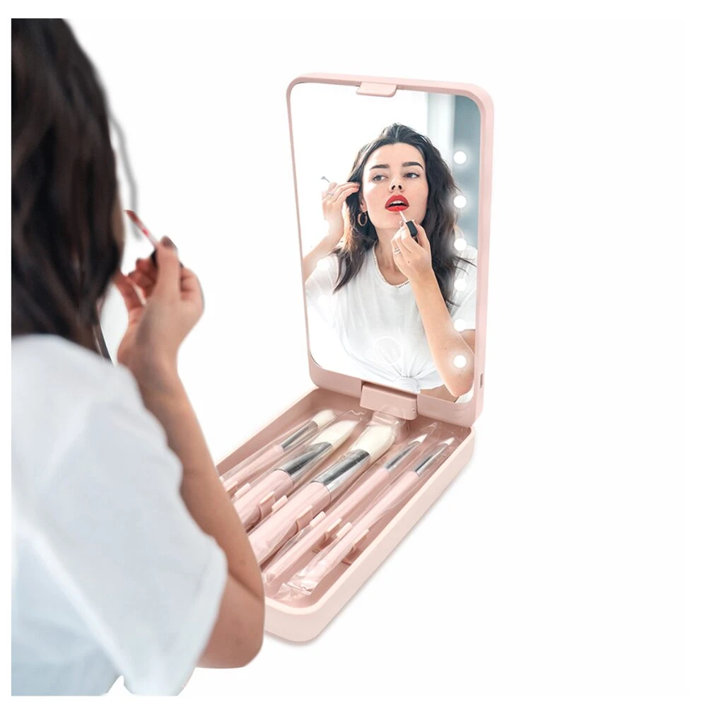 Espejo de maquillaje portátil rosa con luces LED y set de brochas, ideal para retoques.