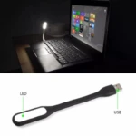 Mini lámpara portátil USB color negro con cuerpo flexible de silicona. Incluye un extremo con conector USB y otro con panel LED, conectada a un portátil.