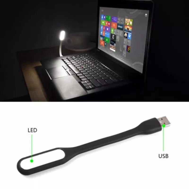 Mini lámpara portátil USB color negro con cuerpo flexible de silicona. Incluye un extremo con conector USB y otro con panel LED, conectada a un portátil.
