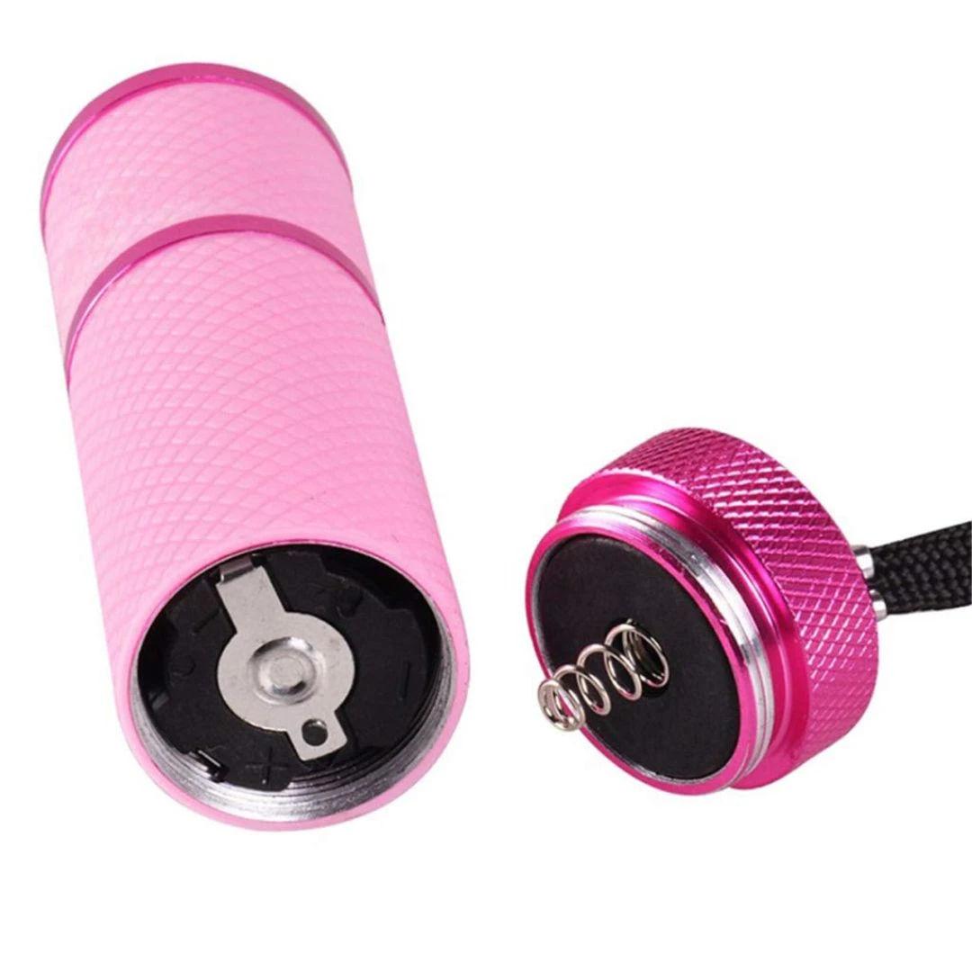 Mini linterna LED UV rosada, con detalle de resortes para batería, lista para usarse.