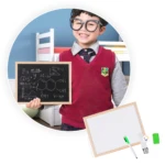 Niño con gafas sostiene tablero doble cara didáctico con fórmulas, otro tablero blanco con marcador y borrador al lado.
