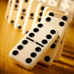 Dominó de mesa blanco con puntos negros en formación escalonada sobre superficie de madera.