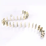 Dominoes blancos de plástico con puntos negros, dispuestos en cadena y curva sobre fondo blanco.