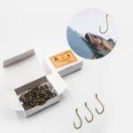 Caja de anzuelos de pesca Nro. 4, dorados, forjados, 100 unidades, con pez capturado en circular.