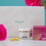Perlas antiedad Lyralá con Vitamina E, envase blanco con hojas rosas, junto a una rosa fucsia y tres cápsulas doradas.