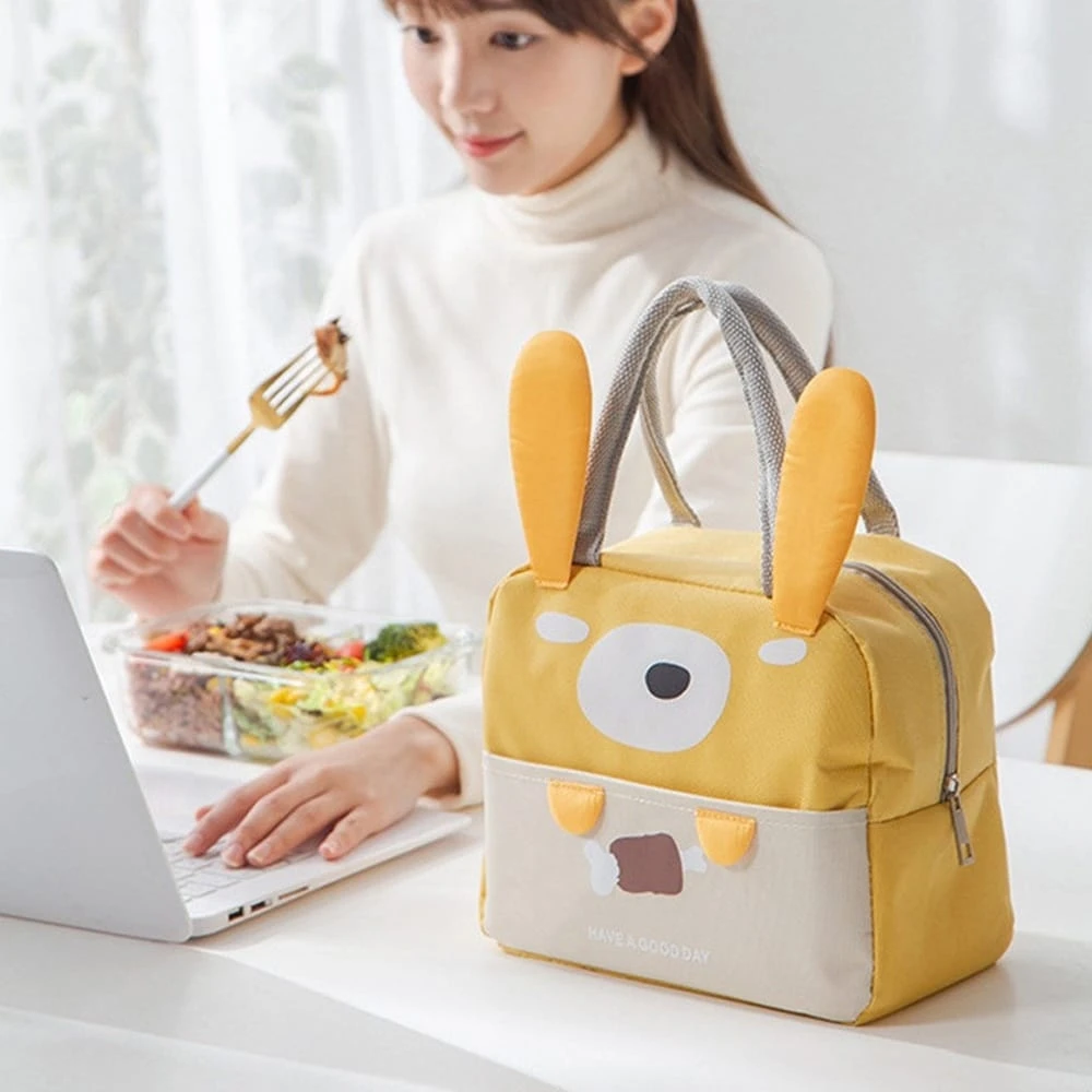 Lonchera térmica amarilla con diseño de conejo, asas grises, ideal para llevar comida.