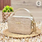 Bolso dama pequeño Cardinale beige textura animal print, con asa y cadena dorada, sobre base de mimbre.