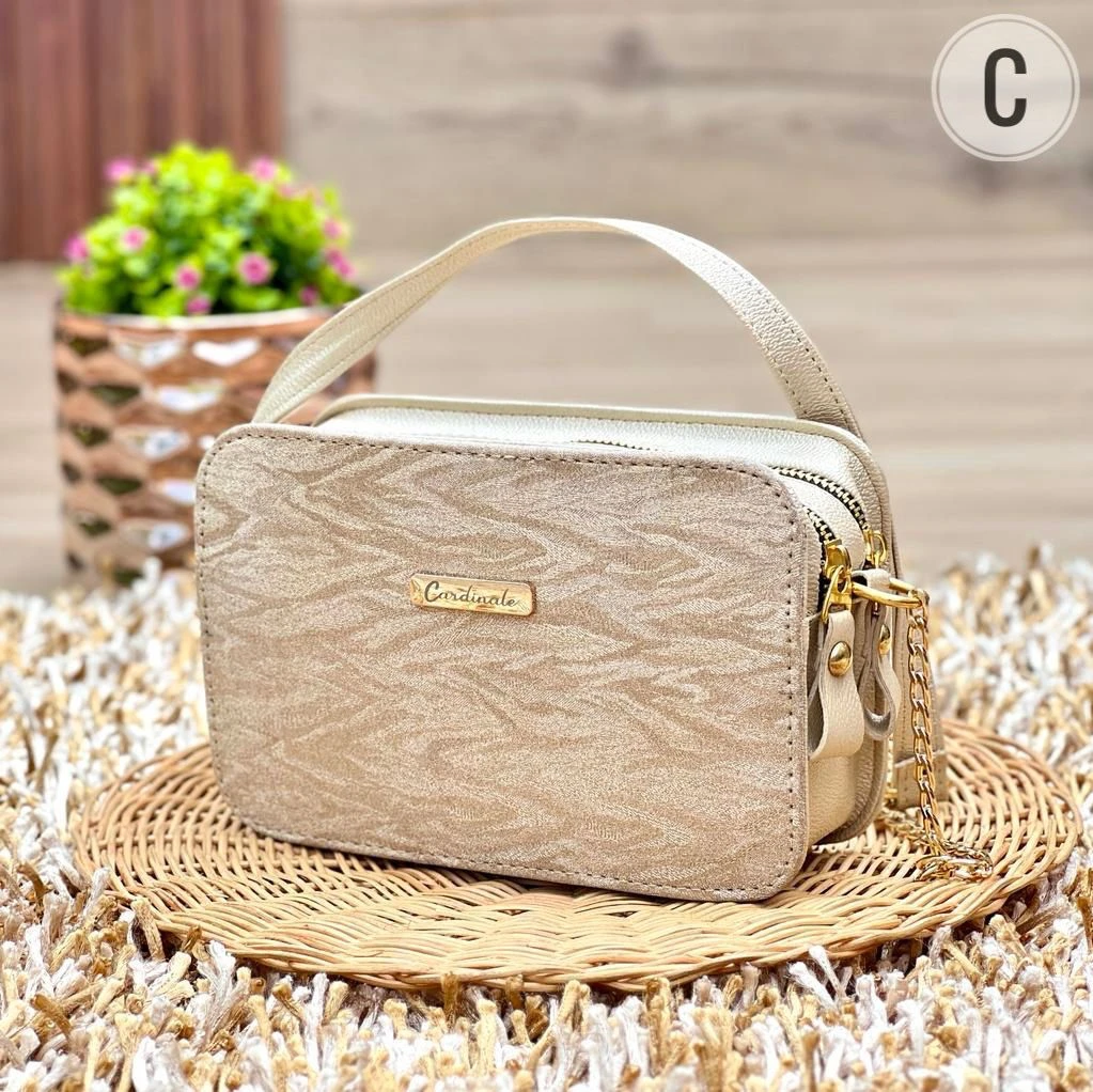 Bolso dama pequeño Cardinale beige textura animal print, con asa y cadena dorada, sobre base de mimbre.