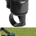 Timbre bicicleta negro clásico con botón superior, visto de cerca y montado en manubrio con fondo de césped.