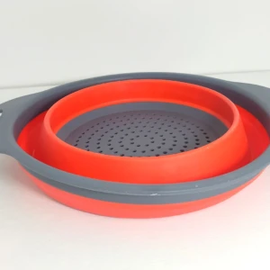 Colador redondo plegable de silicona naranja y gris, con orificios finos y asas.