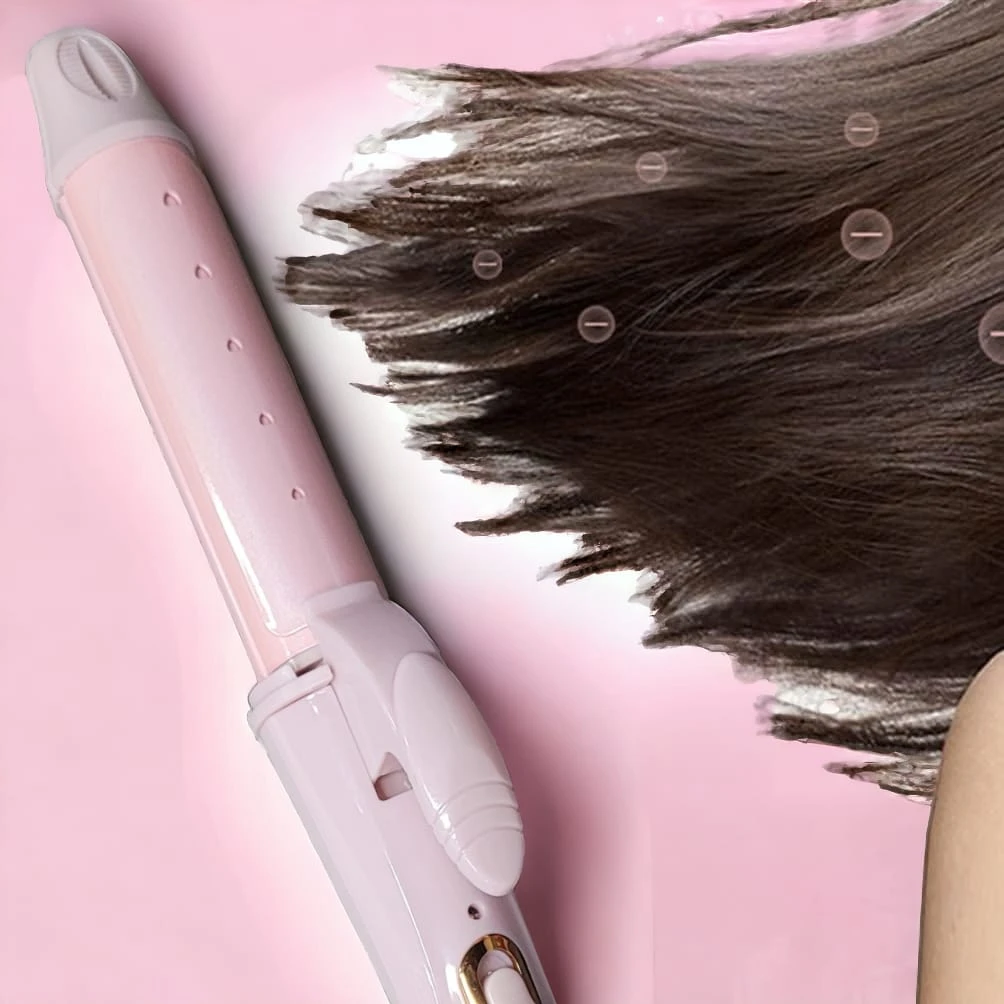 Rizador y alisador profesional 2 en 1 de color rosa pastel sobre fondo rosado, mostrando su placa calefactora mientras peina un mechón de cabello castaño.