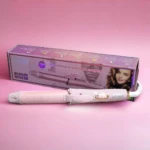 Rizador y alisador de cabello 2 en 1 profesional, color rosa claro, posado frente a su caja de empaque sobre una superficie rosada.