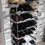 Organizador de zapatos de 9 niveles en color negro con diversos tipos de calzado deportivo y casual en tonos oscuros y claros.
