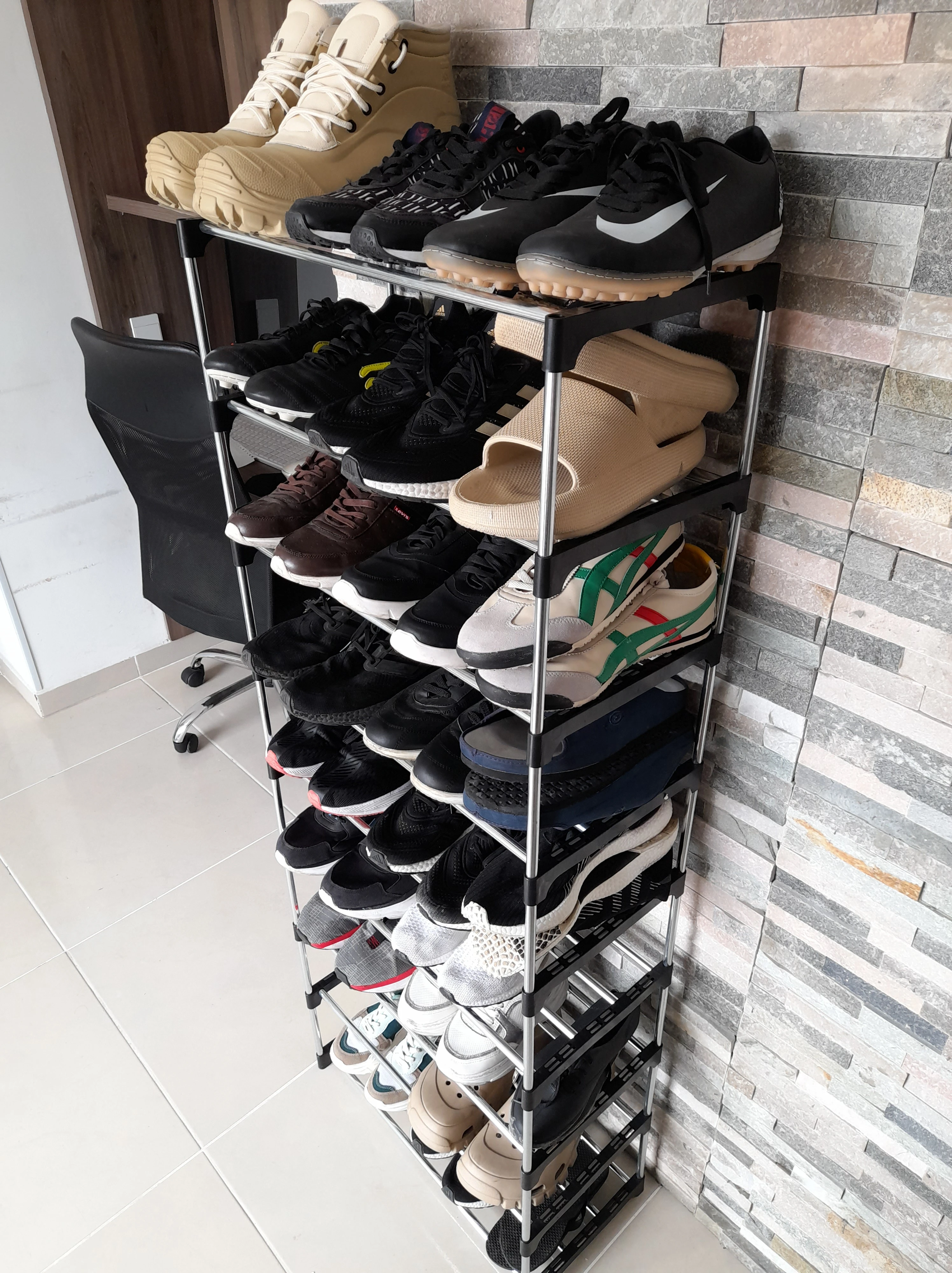 Organizador de zapatos 27 pares 9 niveles con múltiples zapatillas y botas de diversos colores y estilos.