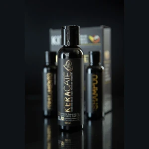 Kit de tratamiento alisante progresivo Keracate en envases negros, compuesto por tres botellas de 120ml y caja exhibidora sobre superficie reflectante.